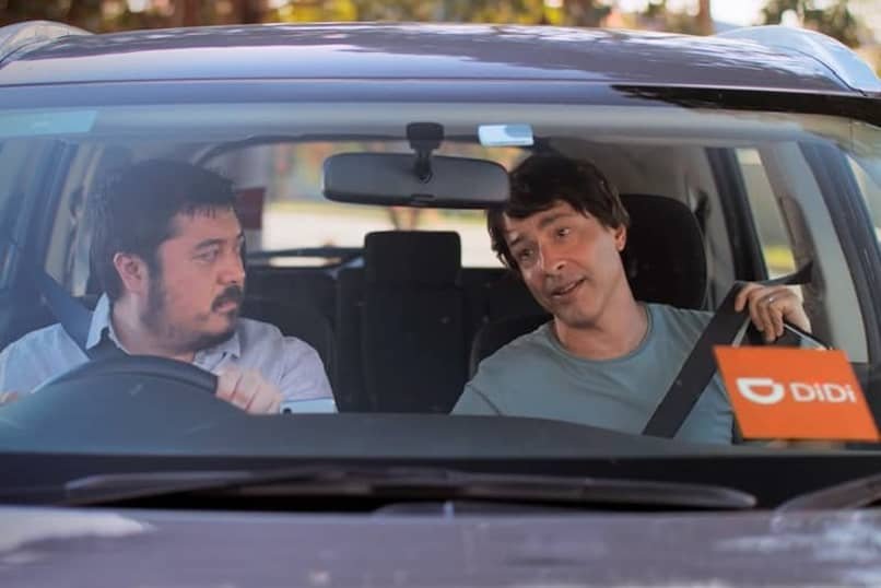 Taux d'achèvement du voyage DIDI et comment fonctionne-t-il ? didi conducteur de voiture avec un homme au volant et un autre sur le siège qui est le passager
