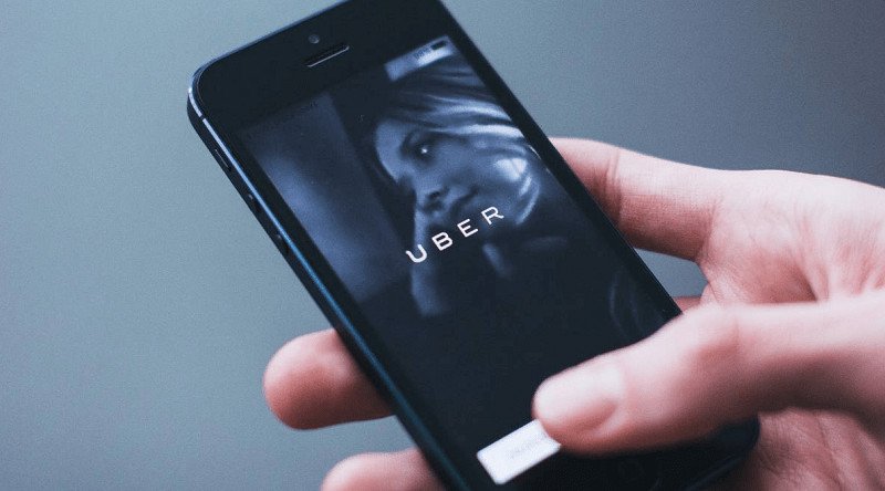 personne utilisant uber depuis son téléphone portable Comment héler un taxi Uber pour commander une course par téléphone
